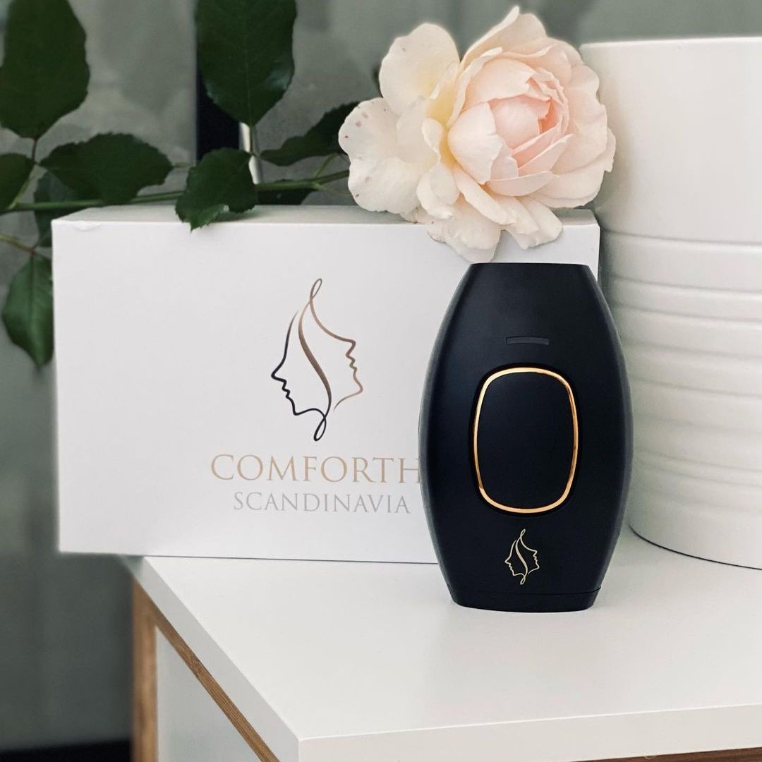 Comforth IPL permanent hårfjerner på et bord ved siden af en blomst